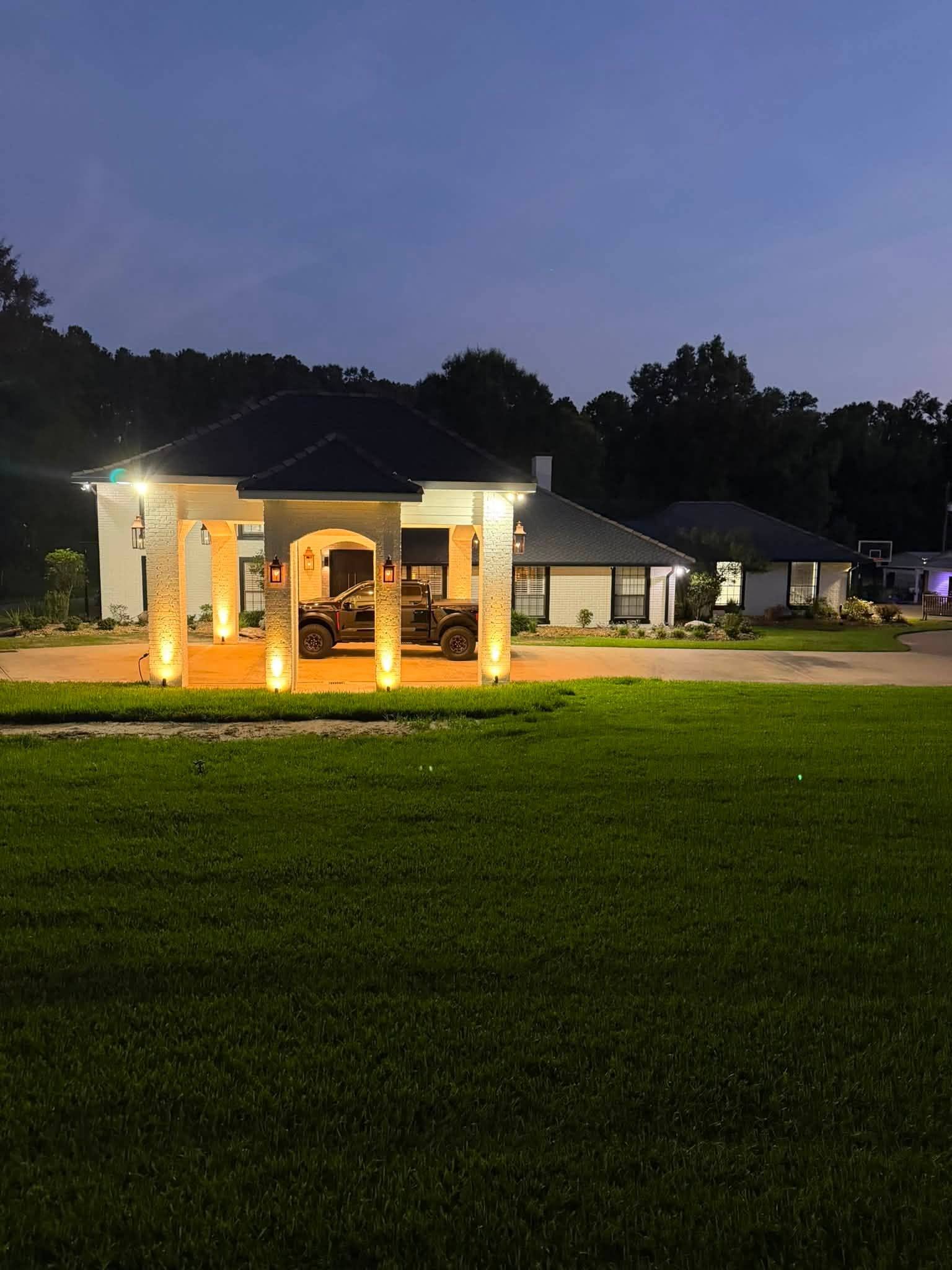 Custom home at twilight with the porte-cochere and landscape lighting lit against a deep blue evening sky