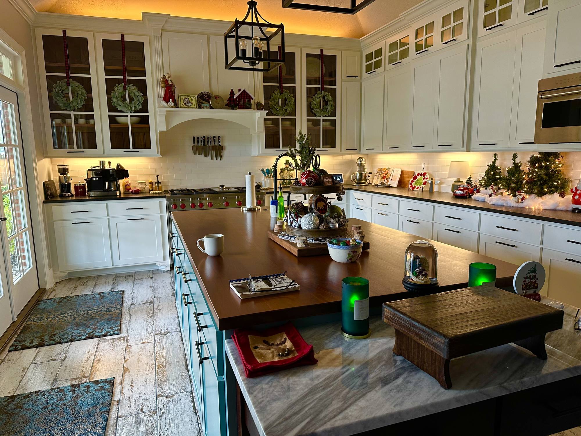 Custom kitchen with glass-front upper cabinets, a painted range hood surround and a walnut-topped island