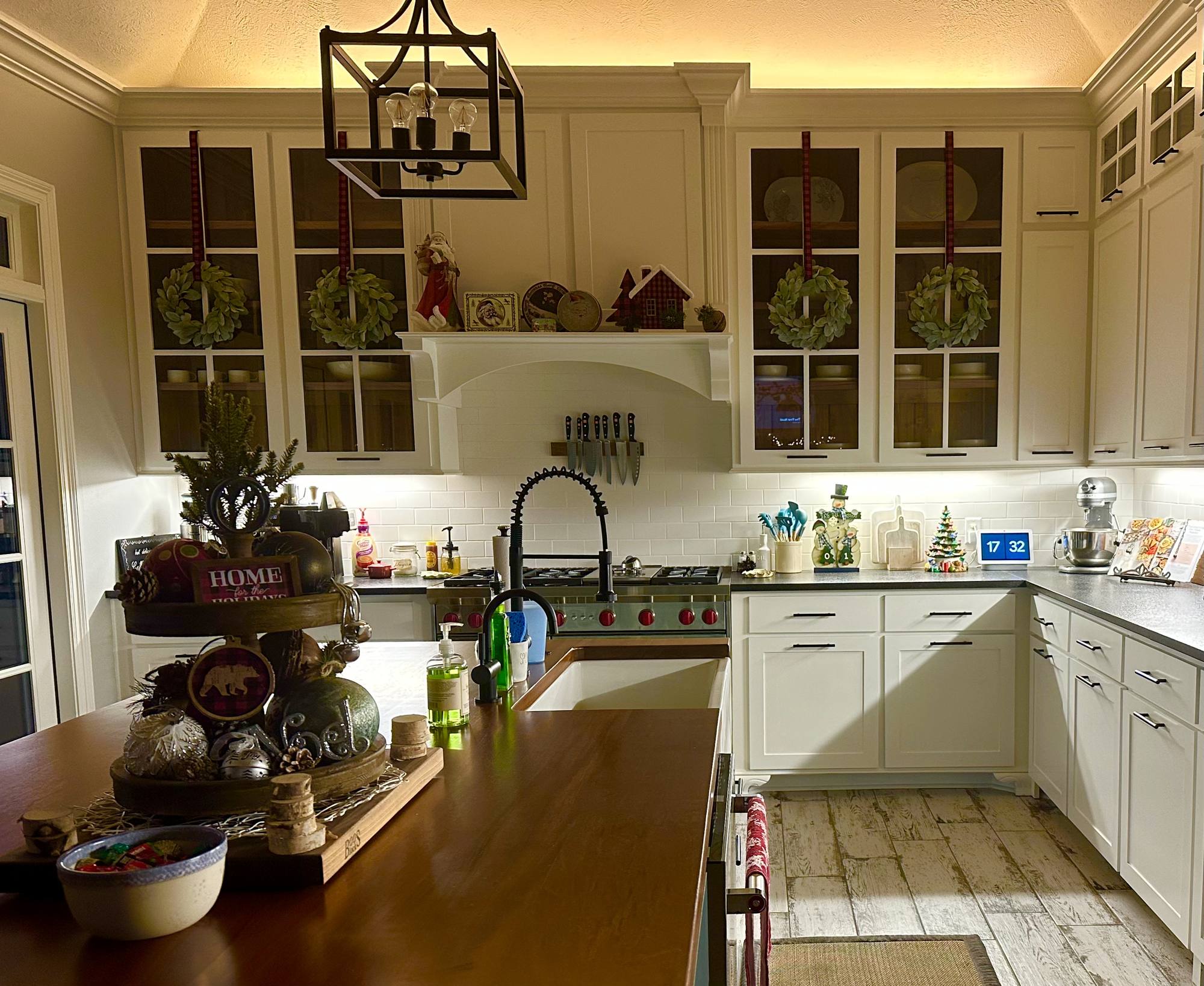 Detail of a painted custom range hood surround flanked by glass-front cabinets above a farmhouse sink