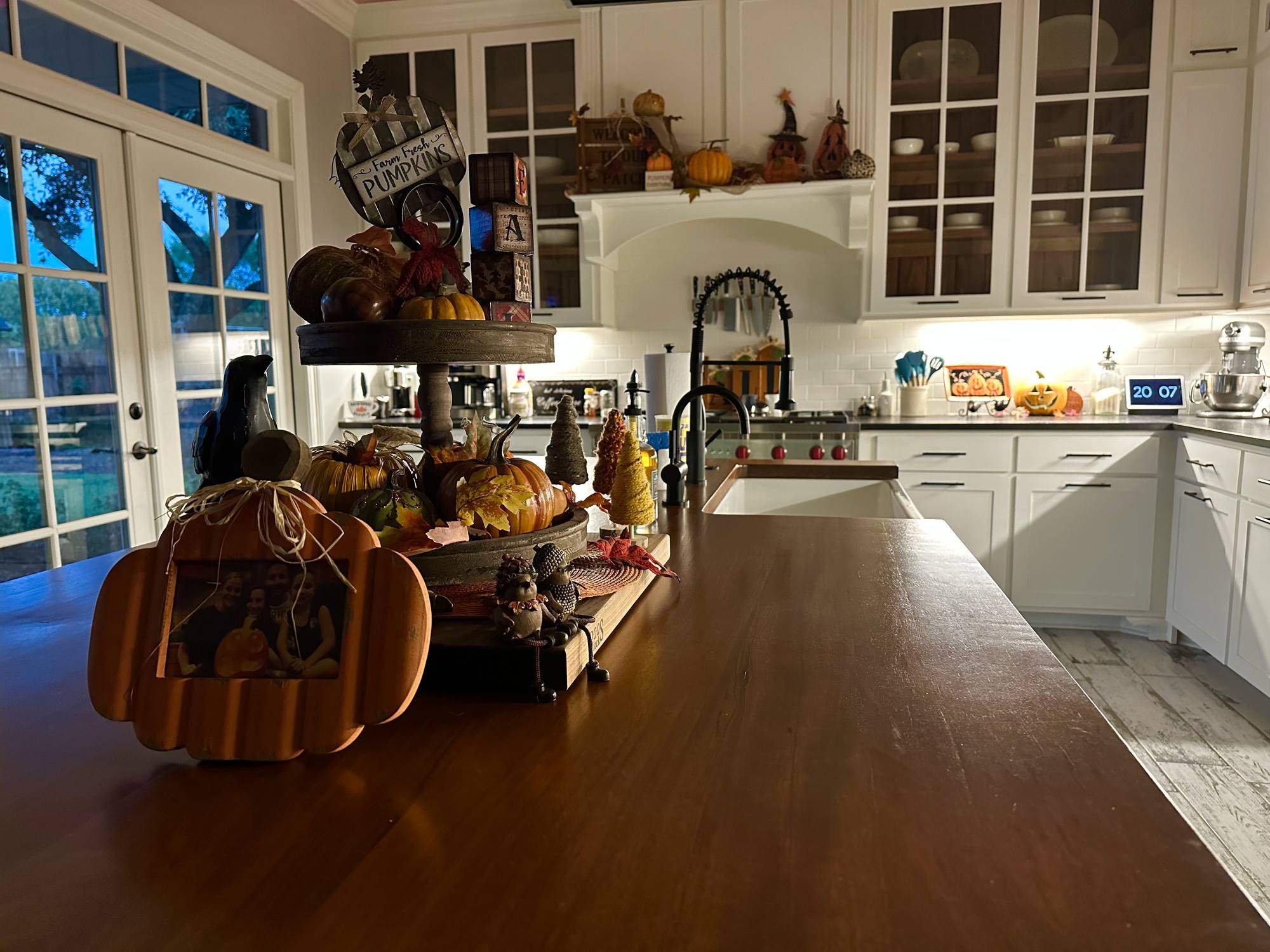 Custom kitchen island with a walnut top, glass-front upper cabinets and a painted hood surround